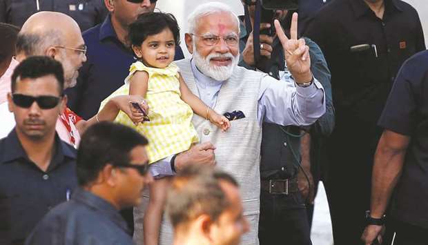 Prime Minister Narendra Modi gestures as he holds the granddaughter of Bharatiya Janata Party (BJP) president Amit Shah after he arrived to cast his vote at a polling station in Ahmedabad yesterday.