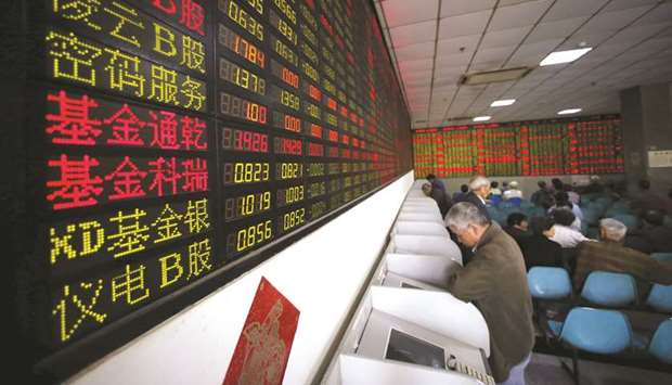 Investors look at computer screens showing stock information at a brokerage house in Shanghai. The Composite index closed down 0.5% to 3,198.59 points yesterday.