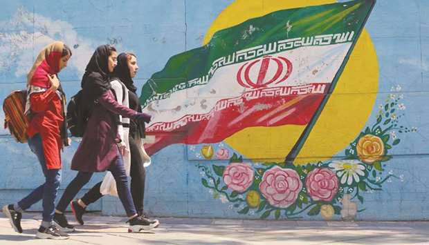 Girls walk in front of a mural showing the Iranian national flag in the centre of the capital Tehran yesterday. The White House said on Monday that its decision is intended to bring Iranu2019s oil exports to zero and squeeze the Gulf stateu2019s principal source of revenue.