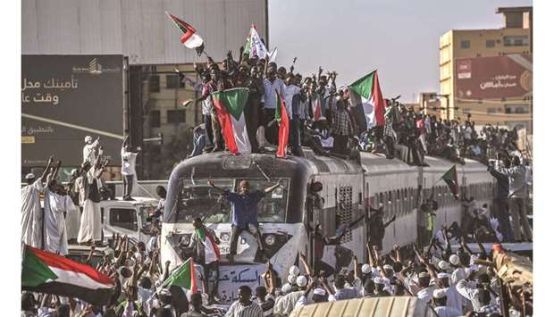 Sudanese protesters from the city of Atbara, sitting atop a train, cheer upon arriving at the Bahari station in Khartoum, yesterday.