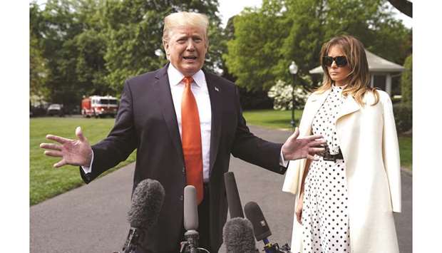 President Donald Trump talks to reporters in Washington yesterday as First Lady Melania Trump looks on.