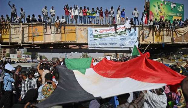 Sudanese protesters wave the national flag during a ,million-strong, march outside the army headquarters in the capital Khartoum
