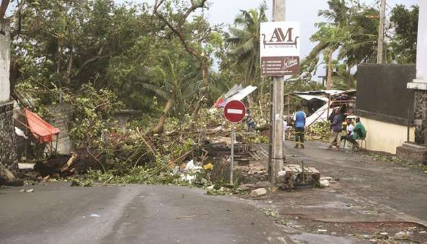 People stand by fallen trees in Moroni yesterday after tropical storm Kenneth hit Comoros before heading to recently cyclone-ravaged Mozambique.
