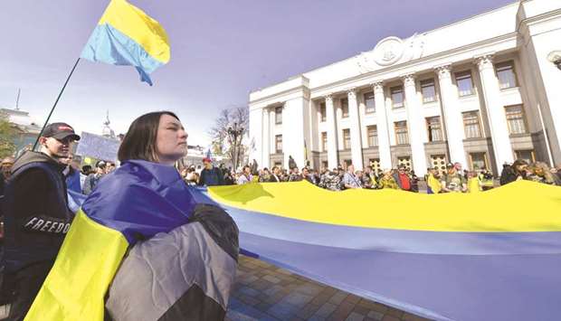 People hold a giant Ukrainian flag during a rally in front of the Ukrainian parliament in Kyiv, as lawmakers voted on a law enforcing the use of Ukrainian in official settings.