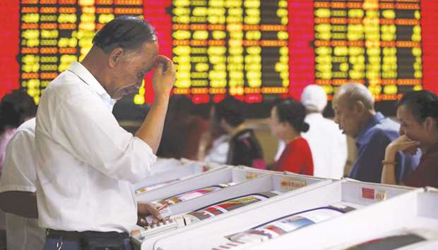 Investors look at computer screens showing stock information at a brokerage house in Shanghai. The Composite index closed down 1.2% to 3,086.40 points yesterday.