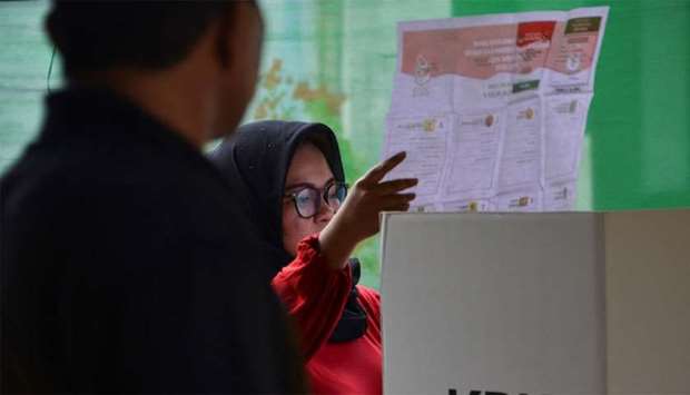 A woman looks at her ballot during a revote due to logistical issues in the country's general election in Banda Aceh