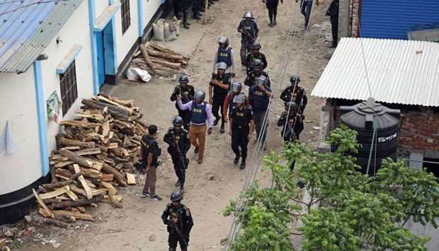 Security personnel walk near a militant den in the Bosila area where militants were killed in Dhaka