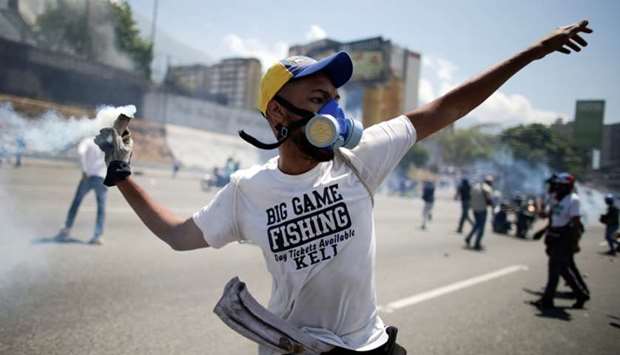 An opposition demonstrator throws back a tear gas canister on a street near the Generalisimo Francisco de Miranda Airbase ,La Carlota, in Caracas, Venezuela