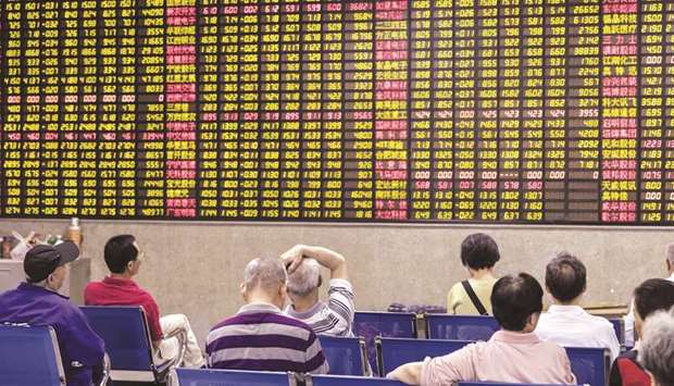 Investors sit in front of an electronic stock board at a securities brokerage in Shanghai. Chinese shares  jumped 0.9% to 3,246.57 points yesterday.