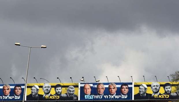 A Blue and White party election campaign poster depicting it's leaders Benny Gantz, Yair Lapid, Moshe Yaalon and Gaby Ashkenazi as well as Israeli Prime Minister Benjamin Netanyahu with members of Israel's far-right political party, Jewish Power, are seen hanging above a main highway in Jerusalem