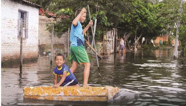 Children play on a raft on a flooded street after heavy rains caused Paraguay River to overflow, in Asuncion, Paraguay.