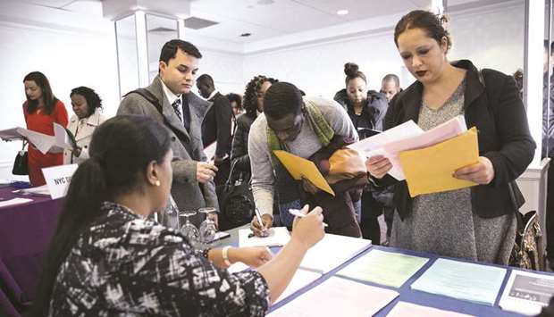 A New York Department of City Administrative Services representative (left), speaks with job seekers during a Catalyst Career Group job fair in New York (file). The Labour Departmentu2019s closely watched monthly employment report yesterday showed a small upward revision to Februaryu2019s meagre job gains.