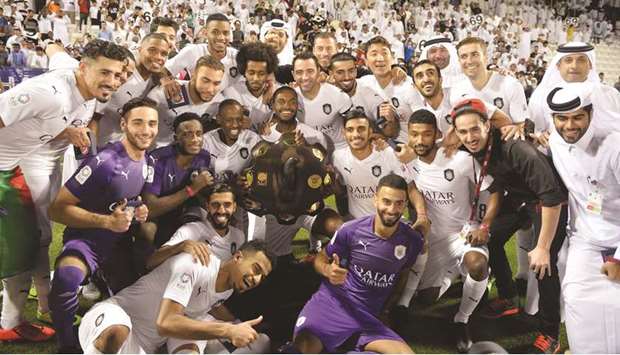 Abdelkarim Hassan holds the Falcon Shield, the symbol of supremacy in Qatar football as Al Sadd players celebrate their 14th title yesterday.