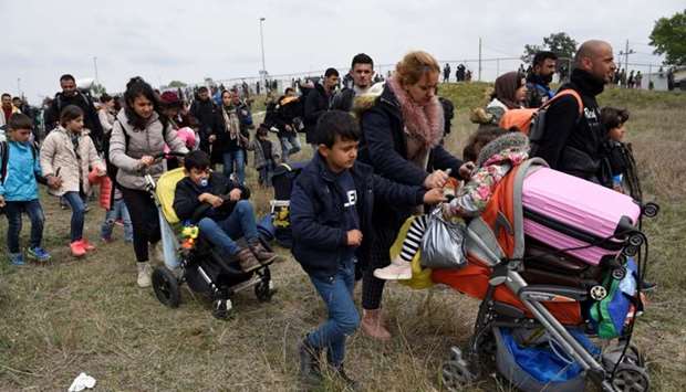 A woman pushes a pram as migrants and refugees, who say that they seek to travel onward to northern Europe, walk away from a camp yesterday near the town of Diavata in northern Greece