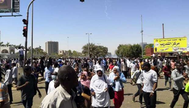 Sudanese protesters run for cover from teargas outside the military headquarters in the capital Khartoum. AFP