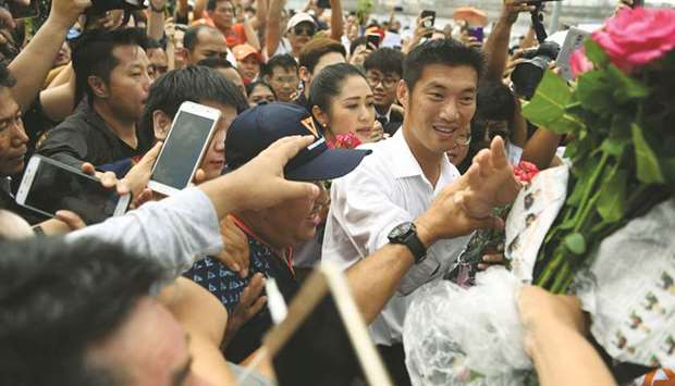 Future Forward Party leader Thanatorn Juangroongruangkit, right, receives flowers from supporters as he arrives at Pathumwan police station to hear sedition charges brought against him by the National Council for Peace and Order (NCPO), in Bangkok yesterday.