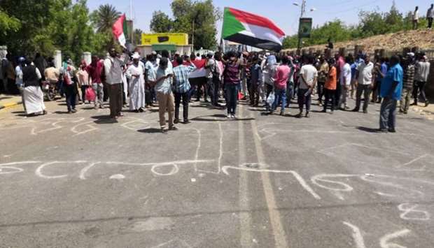 Sudanese protesters raise a national flags and chant slogans as they rally in front of the military headquarters yesterday in the capital Khartoum