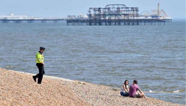 A police officer talks with a couple sitting on the beach in Hove yesterday as warm weather tests the nationwide lockdown and the long Easter weekend begins.