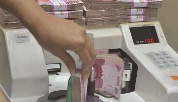 An employee counts Indonesian rupiah banknotes at a money changeru2019s office in Jakarta. The rupiah tumbled to within a whisker of its 1998 record low recently before a relief rally. Options markets indicate the respite will be brief.