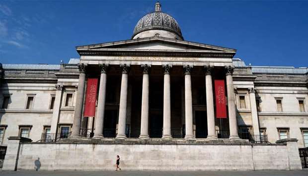 A woman walks outside the National Gallery in an empty Trafalgar Square in central London