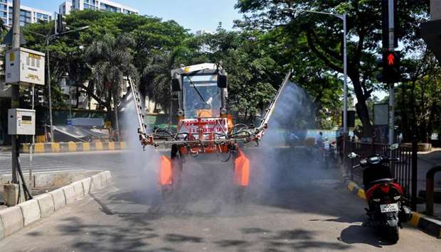Municipal workers spray disinfectant along a street during a government-imposed nationwide lockdown as a preventive measure against the COVID-19 coronavirus in Mumbai