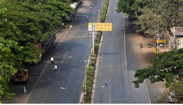 Pedestrians walk on a deserted road during a government-imposed nationwide lockdown in Mumbai yesterday.