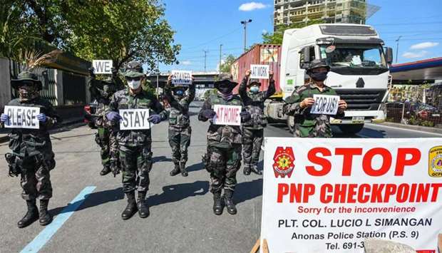 Police personnel hold up placards reminding people to stay at home amid concerns of the spread of the COVID-19 coronavirus in Manila