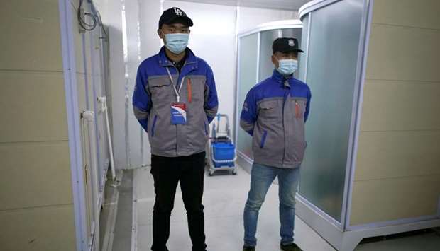 Security personnel wearing face masks stand guard near closed shower rooms inside the Leishenshan Hospital, a makeshift hospital for treating patients with the coronavirus disease (Covid-19), in Wuhan, Hubei province, China