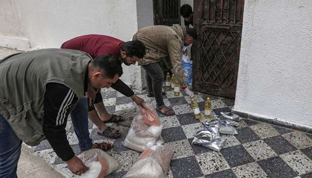 Palestinian workers with the United Nations Relief and Works Agency for Palestinian Refugees (UNRWA), deliver food aid rations to the doorstep of a refugee family home rather than distribute it at a UN centre, in Gaza City, yesterday, as a new measure due to the Covid-19 pandemic.