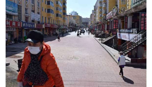 A resident wearing a face mask walks past a shopping street which used to be packed with people in Suifenhe, a city of Heilongjiang province on the border with Russia, as the spread of the novel coronavirus disease (Covid-19) continues in China yesterday.