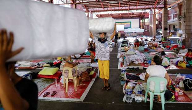 Men carry donated pillows in a  schoolu2019s gymnasium which turned into a shelter for the homeless following the enforcement of a community quarantine in the Philippine main island to contain the coronavirus disease (Covid-19), in Manila.