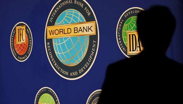 A man is silhouetted against the logo of the World Bank at the main venue for the International Monetary Fund (IMF) and World Bank annual meeting in Tokyo, Oct. 10, 2012. REUTERS
