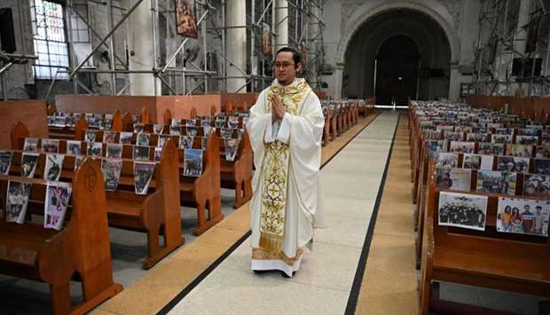 Roman Catholic priest Reverend Father Mark de Leon walks down the aisle through the empty Holy Rosary parish church with photos of parishioners taped on church pews, as part of social distancing measures amidst the COVID-19 pandemic, at the start of a procession for Easter mass in Angeles City, Pampanga province, Philippines.