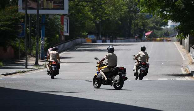 Policemen patrol on motorbikes along a deserted road in New Delhi yesterday.