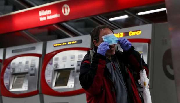 A metro passenger puts on a protective face mask that was given to him, during the lockdown amid the coronavirus disease (Covid-19) outbreak in Madrid, Spain
