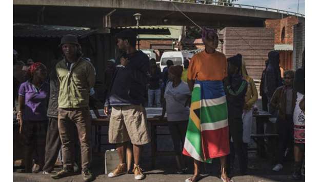 A woman wears a blanket printed with the South African national flag as she queues with others at the Kwa Mai Mai market in the Johannesburg CBD, yesterday during a food distribution.