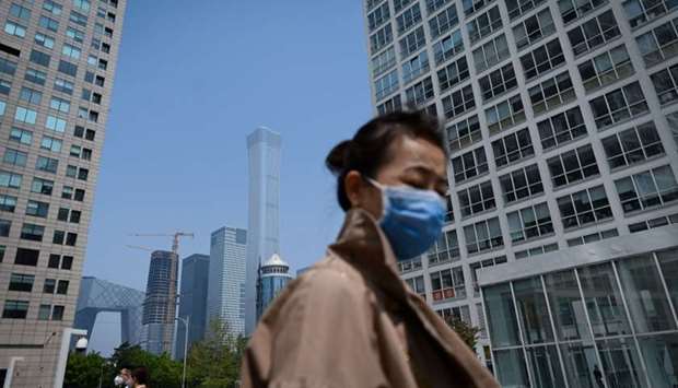 A woman wearing a face mask walks in the Central Business District (CBD) in Beijing