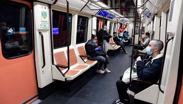 Commuters wearing face masks sit on a train at the Atocha Station in Madrid yesterday as some companies resumed operations at the end of a two-week halt of all non-essential activity.