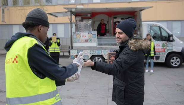 A young volunteer wearing gloves offers hand sanitizer during an information campaign about the coronavirus disease (COVID-19), in the Tensta suburb of Stockholm