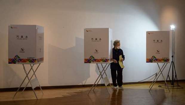 A voter wearing a face mask and gloves amid concerns over the covid-19 novel coronavirus exits a booth to cast a ballot during parliamentary elections at a polling station in Seoul