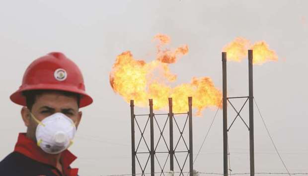 Flames emerge from flare stacks at Nahr Bin Umar oilfield, as a worker wears a protective mask, following an outbreak of coronavirus, north of Basra, Iraq on March 15. Many Middle Eastern countries, notably the Gulf states plus Iraq and Iran, depend heavily on oil revenues to finance their budgets.