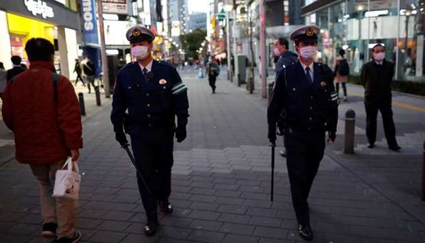 Police officers wearing protective face masks patrol on the street after the government announced the state of emergency for the capital and some prefectures following the coronavirus disease (Covid-19) outbreak, at an entertainment and amusement district in Tokyo