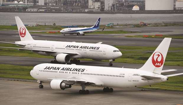 Japan Airlines aircraft and an All Nippon Airways aircraft taxi at Haneda Airport in Tokyo. JAL said yesterday it would operate at 40% of capacity on domestic routes until the end of the month, with ANA reducing it to 49% despite few takers for seats.