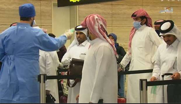 A healthcare professional distributes face masks at the airport to some of the citizens who returned from Jordan.