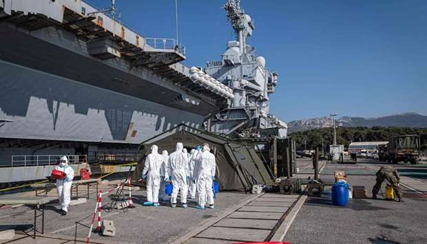 This handout picture released by the Marine Nationale shows a team led by navy soldiers, firefighters and members of a Navyu2019s disinfection special unit, working near the French aircraft carrier Charles de Gaulle after it arrived in the southern French port of Toulon.