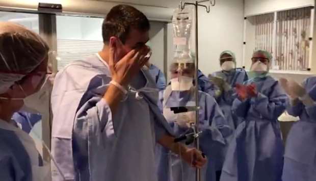 A coronavirus disease patient who has recovered wipes away tears as he's cheered on by hospital staff while walking out of the intensive care unit in Suresnes, France April 14 in this still image taken from social media video