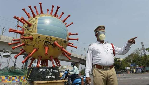 A traffic officer stands beside a coronavirus-themed globe at a traffic junction as he checks commuters travelling during a government-imposed nationwide lockdown as a preventive measure against the COVID-19 coronavirus, in Hyderabad