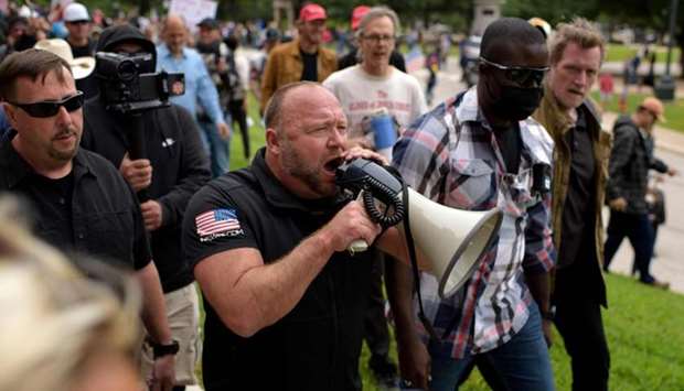 Alex Jones yells into a microphone during the ,Reopen America, rally on at the State Capitol in Austin, Texas