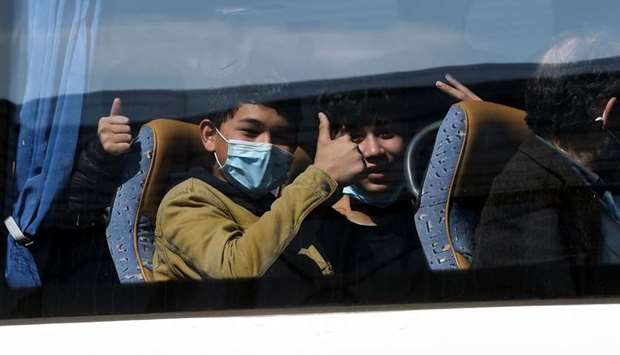 Unaccompanied children from overcrowded migrant camps in Greece gesture as they ride a bus after arriving at the airport in Hanover.