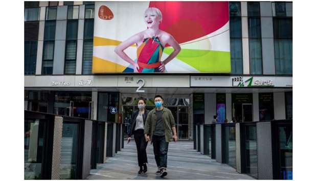 People wearing facemasks amid concerns over the coronavirus walk outside a shopping mall in Beijing.